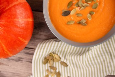 Hokkaido 'nun balkabağı kremalı çorbasının üstünde tahta masa arkasında kabak tohumları ve metin için fotokopi alanı var. Vejetaryen yemeği konsepti, ev yapımı çorba tarifi. Seçici odak