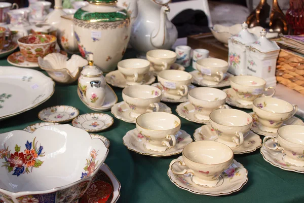 Antigüedades en el mercado de pulgas o festivales: tazas de té de porcelana vintage, vajilla y otras cosas vintage. Objetos coleccionables y concepto de venta de garaje. Enfoque selectivo —  Fotos de Stock