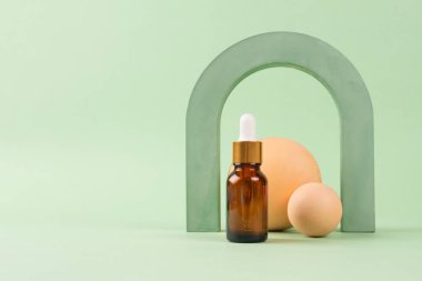 Serumlu, poliglutamik, hiyalüronik asit, nemlendirici ve yaşlanma önleyici yağlı bir şişe görüntüsü. Modern şekilli modaya uygun yaşam bileşimi, kopyalama alanı olan yeşil arkaplana karşı