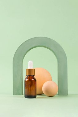 Hiyalüronik asit, serum, nemlendirici ve yüz yağlı damlatıcı görüntüsü. Modern şekilli modaya uygun yaşam kompozisyonu, fotokopi alanı olan yeşil arka plana karşı. Dikey bileşim