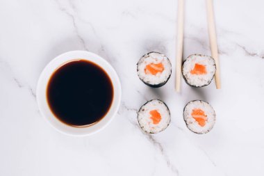 Klasik somon balıklı sashimi, soya sosu ve beyaz mermer masa zemininde yemek çubukları - maki sushi roll, nori maki, futomaki. Asya yemekleri, suşi bar menüsü, çevrimiçi ev yemeği konsepti.
