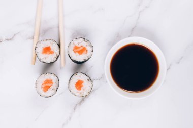 Klasik somon balıklı sashimi, soya sosu ve beyaz mermer masa zemininde yemek çubukları - maki sushi roll, nori maki, futomaki. Asya yemekleri, çevrimiçi ev yemeği konsepti, suşi bar menüsü.