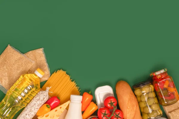 Diversi generi alimentari, donazioni di cibo su sfondo verde con spazio per copiare pasta, verdure, conserve, baguette, olio da cucina, pomodori, formaggio. Concetto di banca alimentare o consegna di cibo. Focus selettivo — Foto Stock