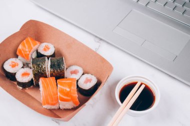 Farklı suşi ruloları, beyaz mermer masa zemininde beyaz mermer kutuda somon balığı, futomaki, uramaki ve hosomaki. Çevrimiçi sipariş gıda ve teslimat konsepti