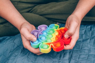 Otistik çocuk gökkuşağı kullanıyor. Kıpır kıpır oyuncak. Kabarcık hareketli duyusal oyuncak, yıkanabilir ve yeniden kullanılabilir silikon stres giderici oyuncak. Özel ihtiyaçları olan çocuklar için stres önleyici bir oyuncak. Ruh sağlığı konsepti