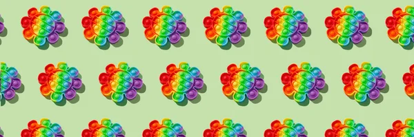 Bannermuster mit Regenbogenpop-Fidget-Spielzeug auf grünem Hintergrund. Push Bubble Fidget Sensorspielzeug - waschbares und wiederverwendbares Stressabbauspielzeug. Antistress-Spielzeug für Kinder oder Erwachsene — Stockfoto