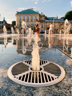 Lviv, Ukrayna - 2 Eylül 2020: insanlar gün batımında Lviv 'deki Mytna Meydanı' nda yaya çeşmesinin yanında yürüyorlar. Seçici odak