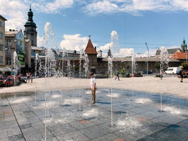 Lviv, Ukrayna - 2 Eylül 2020: turistler ve yerel halk gün batımında Lviv 'deki Mytna Meydanı' ndaki yaya çeşmesinin yanında dinleniyorlar. Seçici odak