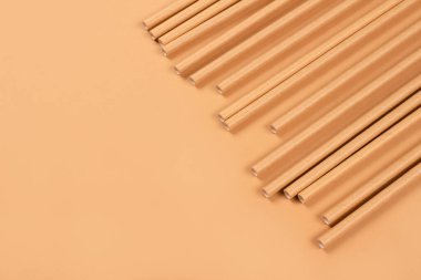 Çevre dostu kağıdın fotokopi alanı olan açık kahverengi kağıt arka planda pipet içerkenki görüntüsünü kapat. Sürdürülebilir kağıt paketleme konsepti. Seçici odak