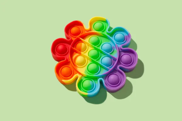 Rainbow pop it fidget toy on green background. Push bubble fidget sensory toy - washable and reusable stress relief toy. Antistress toy for children or adult. Mental health concept