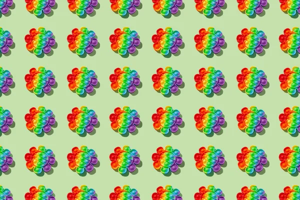 Pattern made with rainbow pop it fidget toy on green background. Push bubble fidget sensory toy - washable and reusable stress relief toy. Antistress toy for children or adult. Mental health concept — Stock Photo, Image