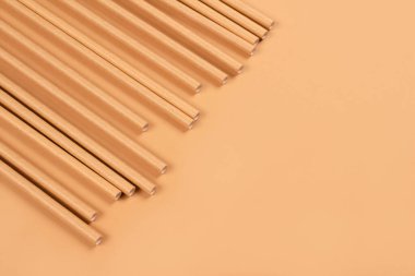 Çevre dostu kağıdın fotokopi alanı olan açık kahverengi kağıt arka planda pipet içerkenki görüntüsünü kapat. Sürdürülebilir kağıt paketleme konsepti. Seçici odak