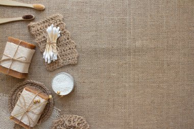 Farklı doğal banyo aletleri, sürdürülebilir yaşam tarzı, sıfır atık kavramı. Ahşap diş fırçaları, bambu çubukları, sabun, diş pudrası ve kumaş kaplamalı jüt çamaşır.