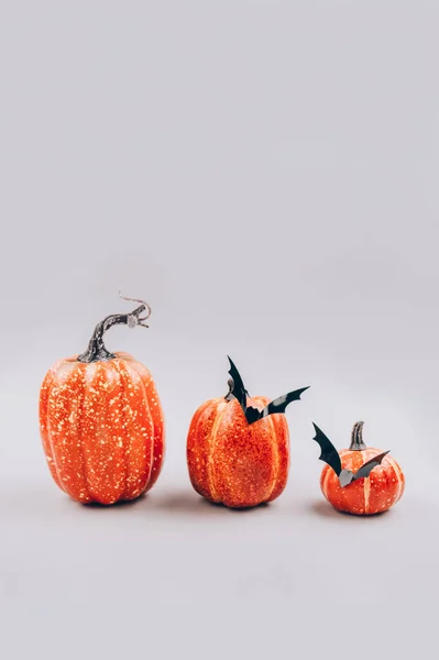 Imagen vertical, mínimo miedo y concepto de Halloween. Calabazas naranjas decorativas con murciélagos sobre fondo gris claro con espacio para copiar. Decoraciones de Halloween o invitación a la fiesta. Enfoque selectivo — Foto de Stock