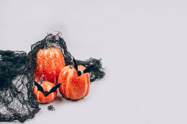 Mínimo Halloween concepto de miedo y divertido. Calabazas naranjas decorativas con bigote en forma de murciélago sobre fondo gris claro con espacio para copiar. Decoraciones de Halloween o invitación a la fiesta. Enfoque selectivo — Foto de Stock