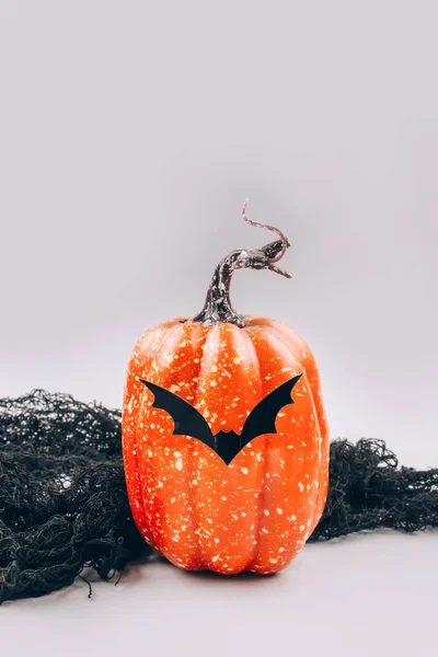 Imagen vertical con calabaza naranja decorativa con bigote en forma de murciélago sobre fondo gris claro con espacio para copiar. Halloween concepto aterrador y divertido. Decoraciones de Halloween. Enfoque selectivo —  Fotos de Stock