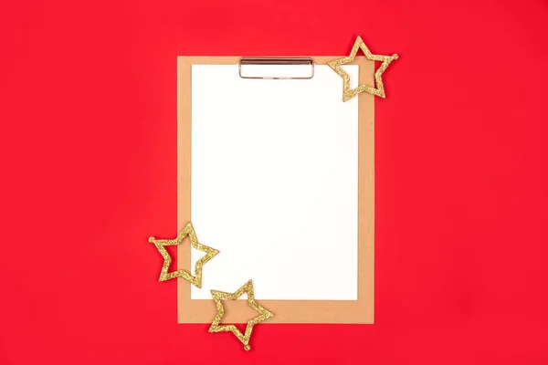 Parlak kırmızı arka planda altın yıldız süslemeleri olan boş not kağıdı. Düz yatış tarzı, planlama konsepti. Seçici odak — Stok fotoğraf