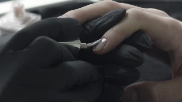 Føreren i sorte latexbeskyttelseshandsker dypper en børste i et rør med en beige lak. Skønhedssalon, Manicure – Stock-video