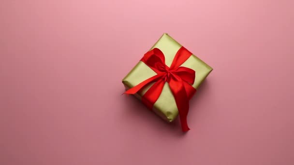 Regalo festivo in confezione d'oro e fiocco rosso su fondo rosa. Un piacevole regalo e sorpresa per i propri cari. — Video Stock