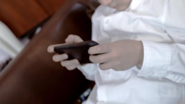 Çocuk akıllı bir telefon çalıyor. Elleri yakın çekim. Oyunlara bağımlılık. Sanat sesi.