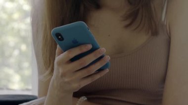 15 Ağustos 2018. Yakın plan. Kız elinde mavi bir çantada iPhone tutuyor ve üzerine bastırıyor. Editör belgeseli.