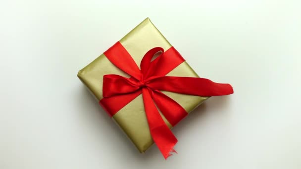 Geschenk in einer Goldverpackung mit roter Schleife und Schleife auf hellem Hintergrund. — Stockvideo