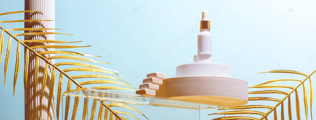Monumental composition with cosmetic oil for the face with catwalks, stairs, palm leaves and geometric shapes in blue and gold colors, beauty concept. Banner