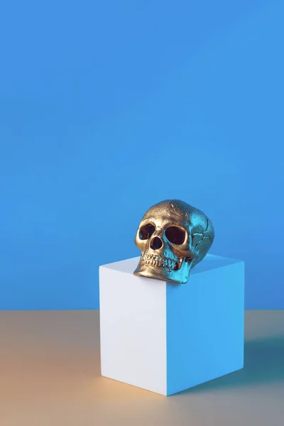 Golden skull and geometric shapes on a blue background, Halloween concept.