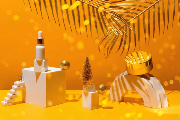 Guldsammensætning med fløde og serum, geometriske former og juletræ, på gul baggrund med palmeblade, skønhedskoncept og kosmetik. - Stock-foto