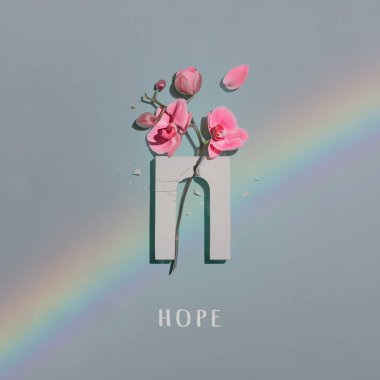 Nane arkaplanda kırık kemer ve pembe orkide çiçekli kompozisyon.