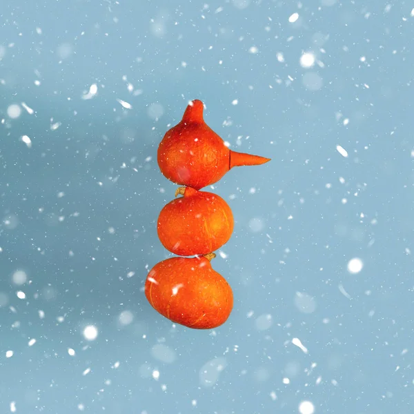 Sněhulák s mrkvovým nosem ze tří oranžových dýní na modrém pozadí. Halloween koncept — Stock fotografie