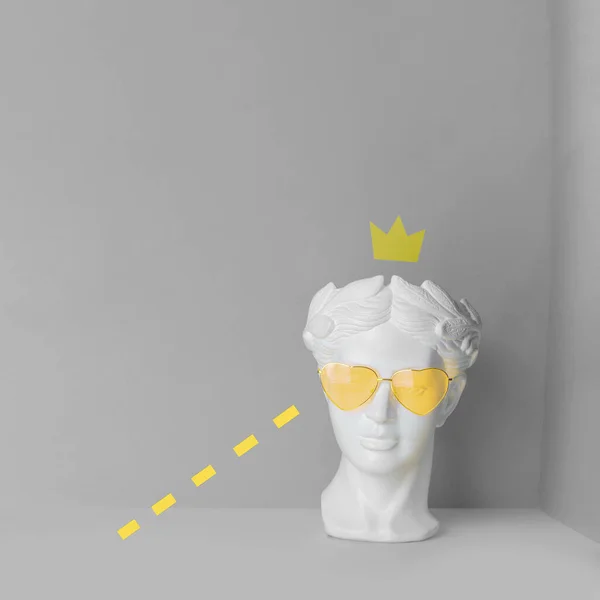 Escultura blanca de una cabeza antigua en gafas amarillas con corazones. Sobre un fondo geométrico de dos colores. — Foto de Stock