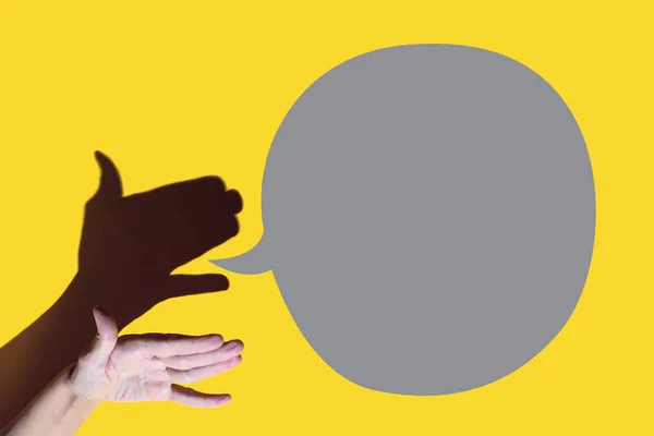 Театру тіней. рука показує собаку з відкритим ротом. Шес розмовляє на жовтому тлі — стокове фото