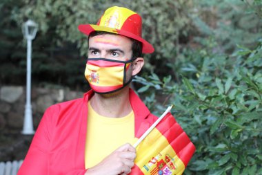 İspanya bayrağı ve sağlık maskesi takmış yakışıklı genç bir adamın portresi.