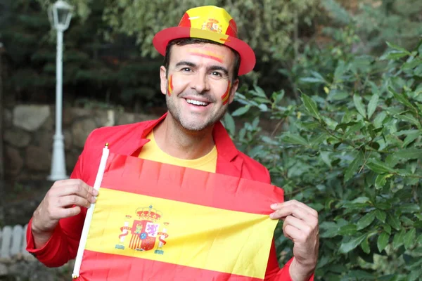 portrait of handsome young man in clothes colored in Spain flag on nature