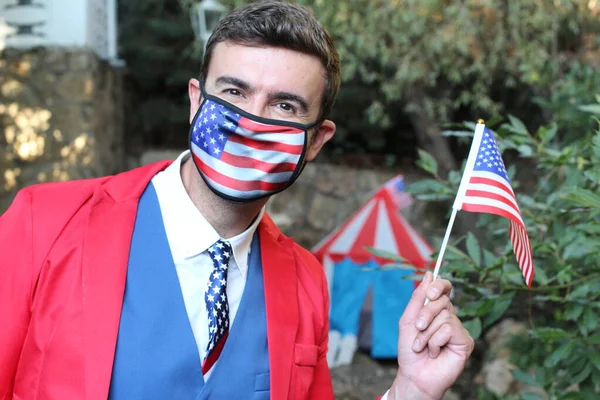 portrait of man in red and blue suit with usa flag and mask on nature