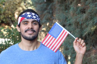 Parkta Amerikan bayrağı ve bandosu olan yakışıklı bir gencin portresi.