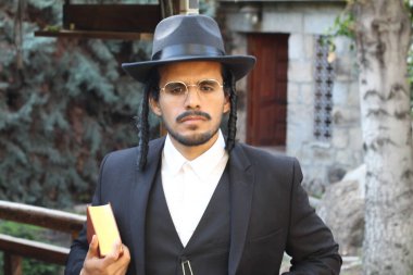 Geleneksel şapkalı yakışıklı hahamın doğal arka planda Tanakh ile yakın plan portresi.