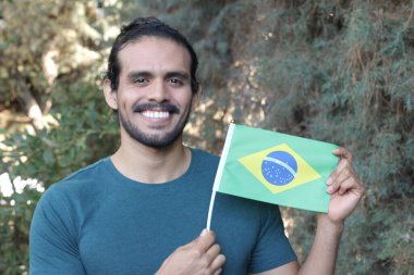 Parkta Brezilya bayrağı taşıyan yakışıklı bir gencin portresi.