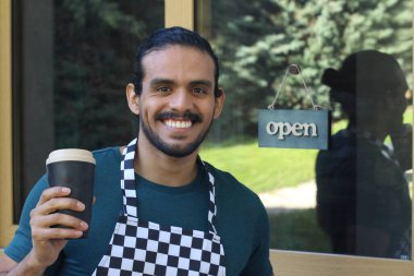 Kapının önünde kağıt kahve fincanı olan, üniformalı, yakışıklı, küçük işletme sahibinin portresi.