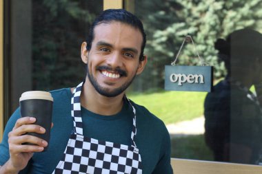Kapının önünde kağıt kahve fincanı olan, üniformalı, yakışıklı, küçük işletme sahibinin portresi.