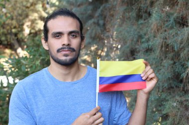 Parkta Kolombiya bayrağı taşıyan yakışıklı bir gencin portresi.