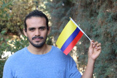 Parkta Kolombiya bayrağı taşıyan yakışıklı bir gencin portresi.