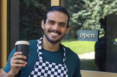 Kapının önünde kağıt kahve fincanı olan, üniformalı, yakışıklı, küçük işletme sahibinin portresi.