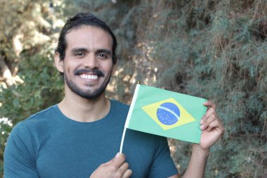 Parkta Brezilya bayrağı taşıyan yakışıklı bir gencin portresi.