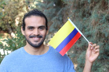 Parkta Kolombiya bayrağı taşıyan yakışıklı bir gencin portresi.