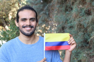 Parkta Kolombiya bayrağı taşıyan yakışıklı bir gencin portresi.