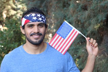 Parkta Amerikan bayrağı ve bandosu olan yakışıklı bir gencin portresi.