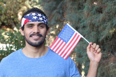 Parkta Amerikan bayrağı ve bandosu olan yakışıklı bir gencin portresi.