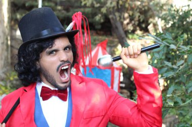 Sirk çadırının önünde kırmızı kostümlü yakışıklı sirk sihirbazının portresi.